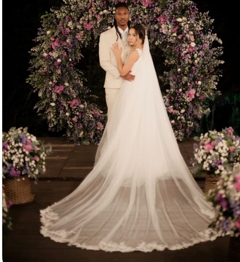 Sarinha e seu par diante do arco de flores à noite